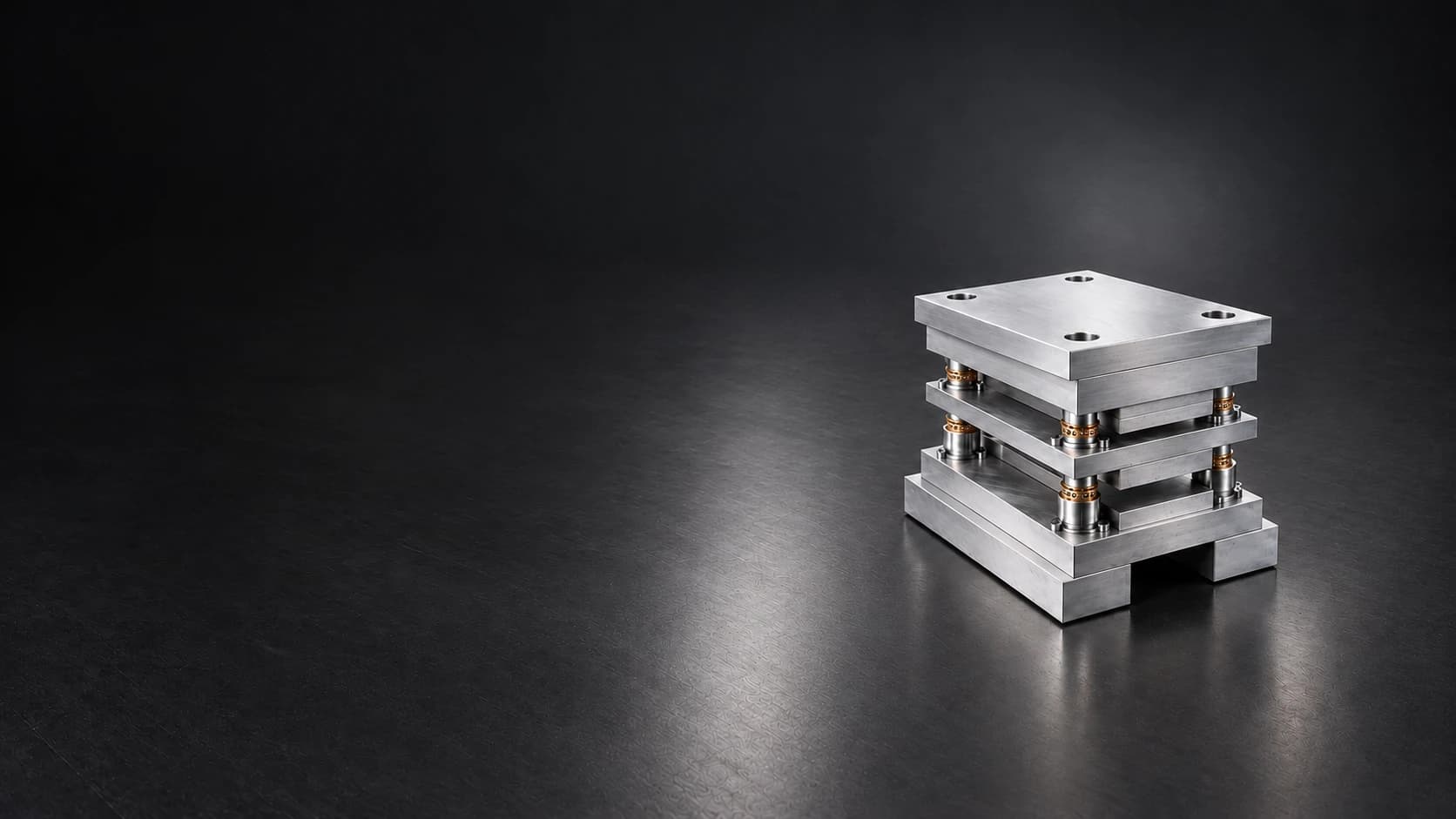 Small steel die set with guide pillars on a dark graphite surface