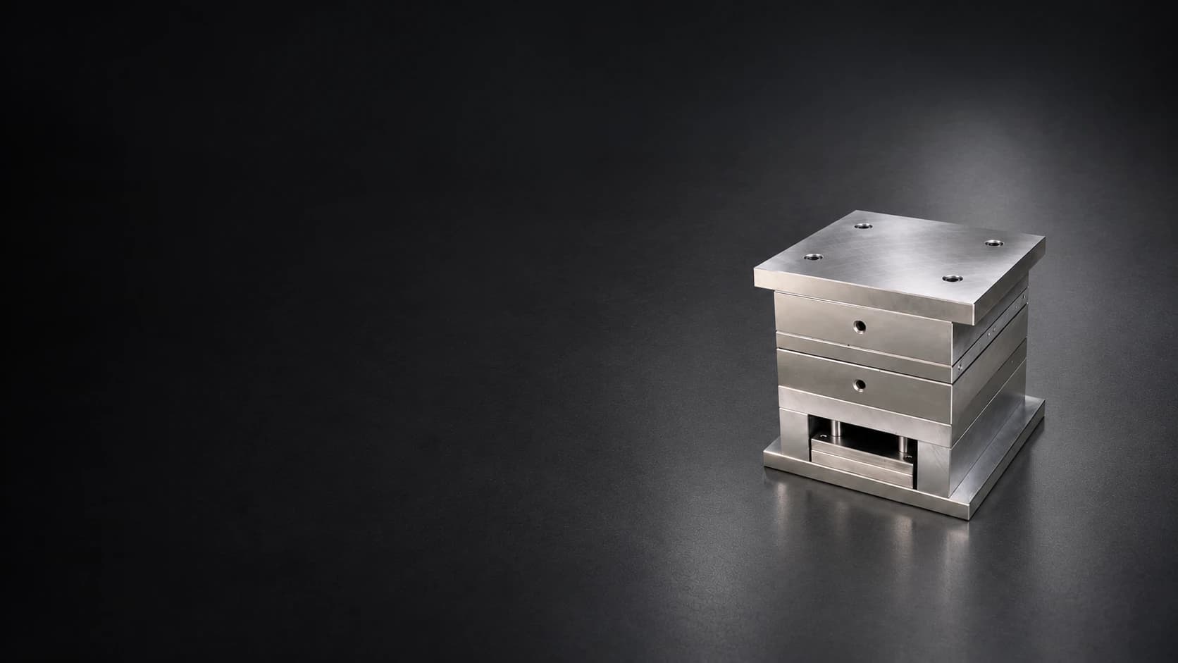 Small assembled mold base on a dark graphite surface