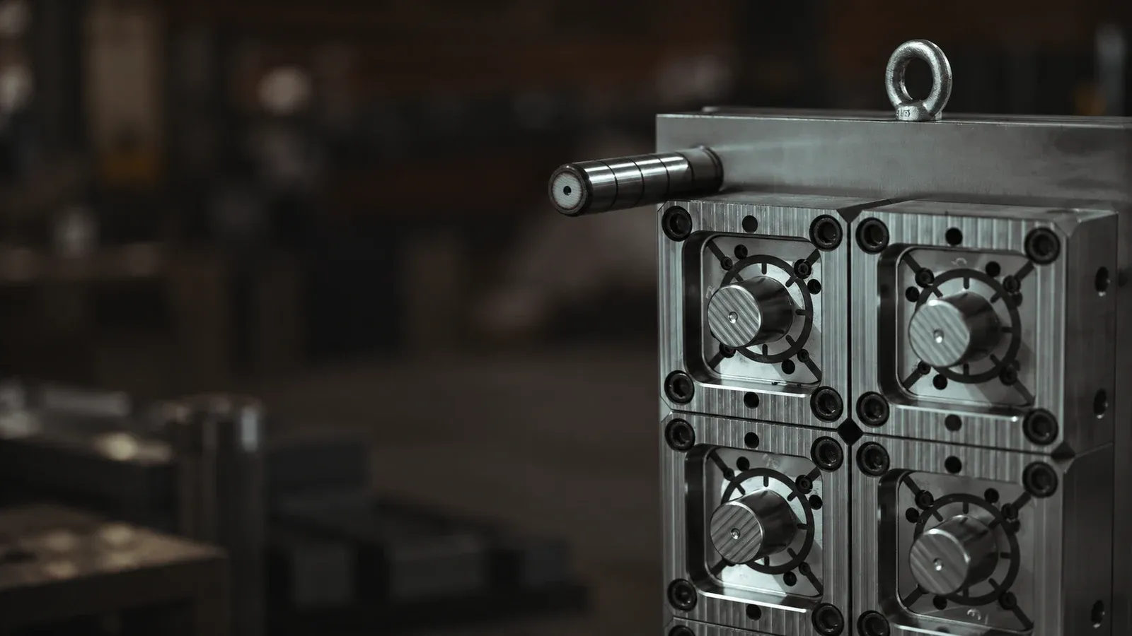 Machined steel injection mold assembly with cavities, fasteners and a guide pin in a workshop